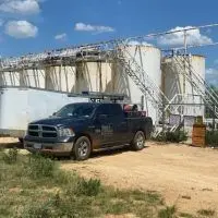Long's Pest Control pickup parked by oilfield storage tanks