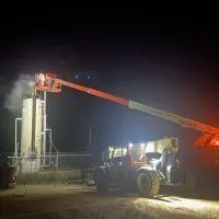 Crew on a boom lift servicing an oilfield tower at night
